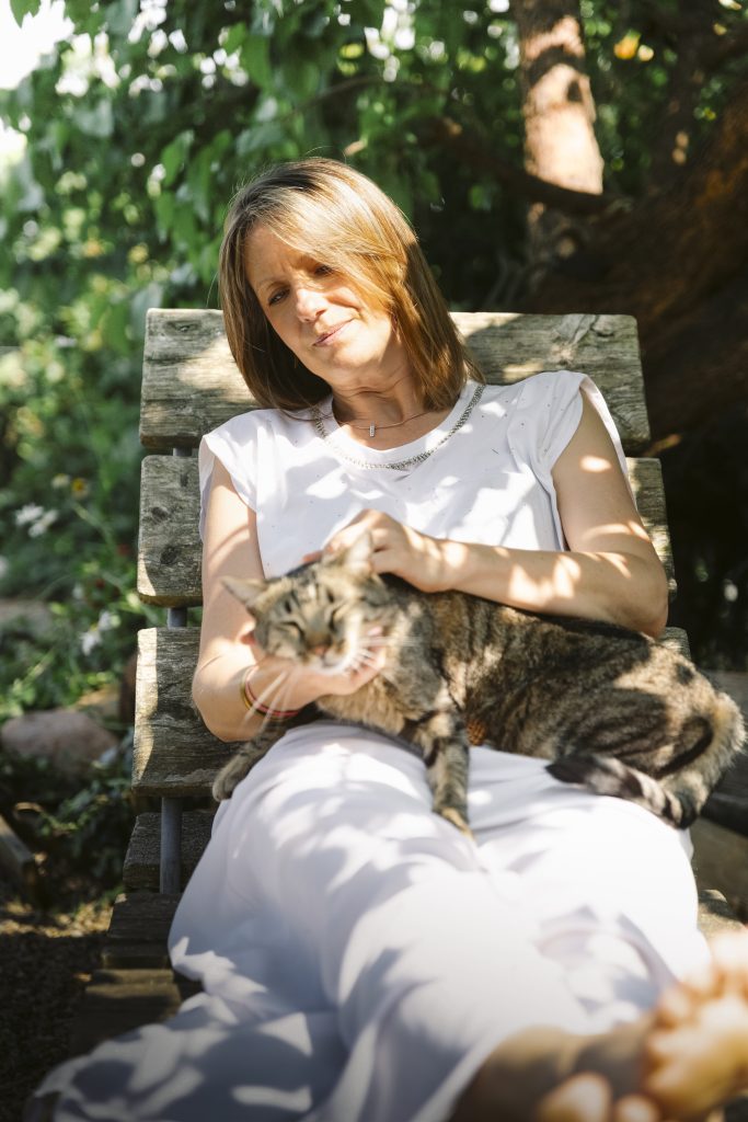Moment de détente de Laurence sur une chaise longue à l’ombre d’un arbre, accompagnée de son chat Tichat. Une scène de douceur et de complicité