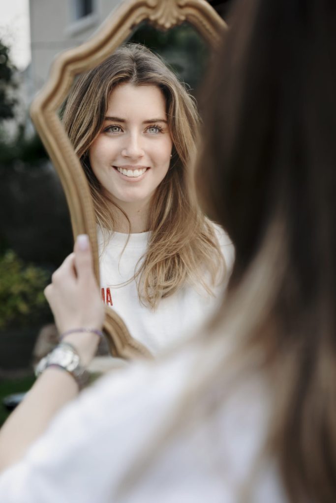 Visage d’une jeune femme lumineuse et souriante après un soin énergétique, symbolisant la meilleure version de soi.