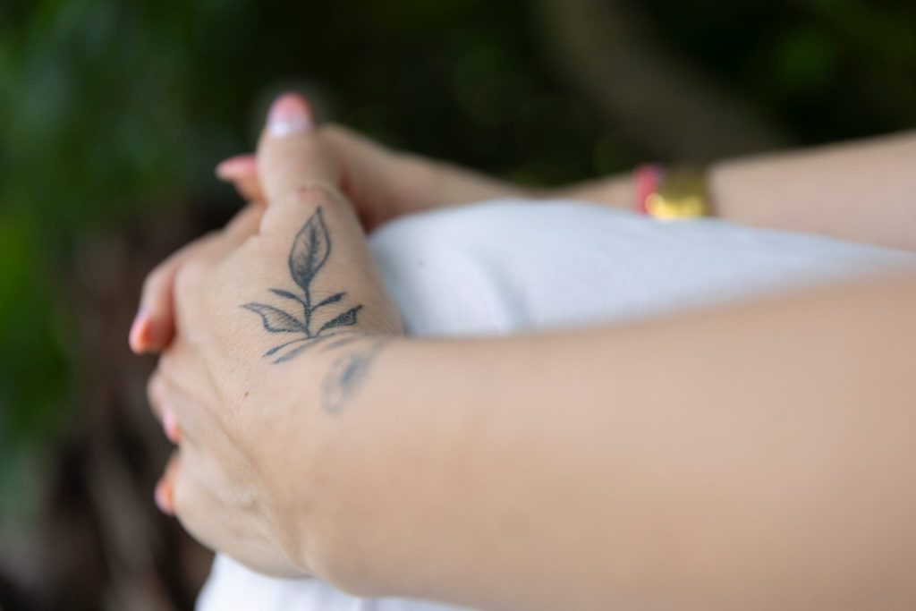 Mains entrelacées de Laurence Rey avec un fond naturel verdoyant.