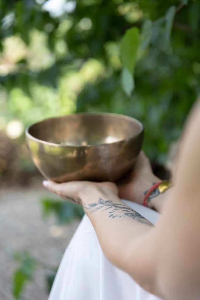 Avant-bras de Laurence Rey tenant un bol tibétain dans la nature.