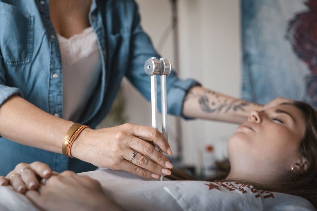 Laurence Rey pratique un soin énergétique au diapason sur une patiente allongée sur le dos