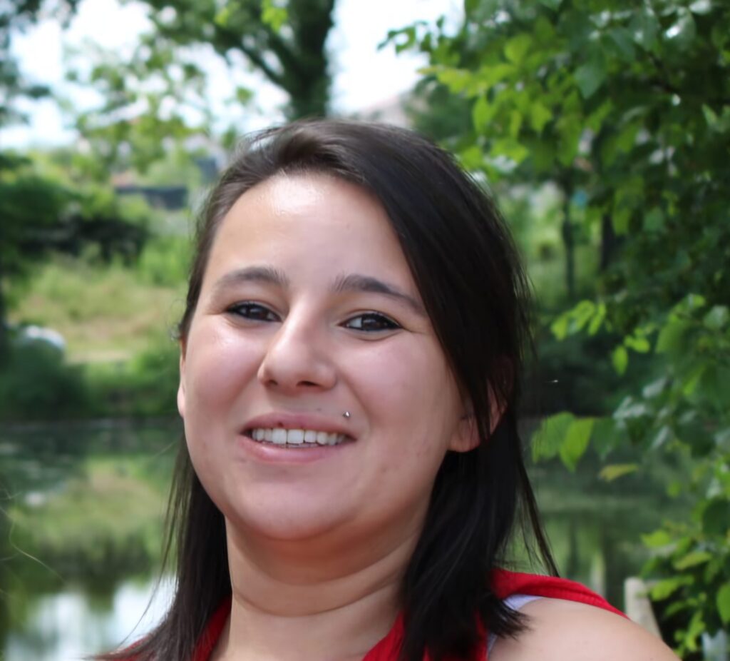 Portrait de Samantha avec un haut rouge en nature pour son témoignage