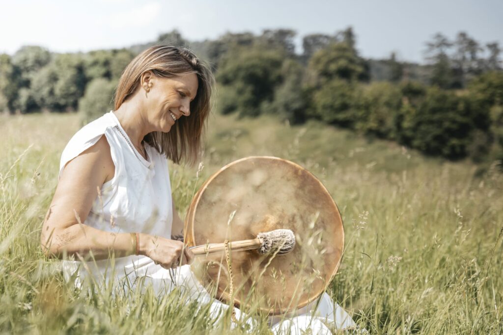 Laurence assise au milieu d'une belle prairie où elle peut laisser chanter son tambour